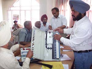 Poll officials check an electronic voting machine during the last day of four-day training camp in Patiala