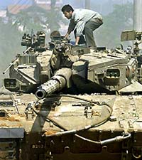 A Palestinian youth jumps into an Israeli tank to throw stones during an Israeli raid at Deir al Balah town
