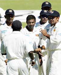 Sri Lanka's Muttiah Muralitharan is congratulated by team-mates after taking the wicket of Zimbabwe's Tatenda Taibu
