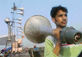 A labourer carries a loudspeaker on the concluding day of the election campaign