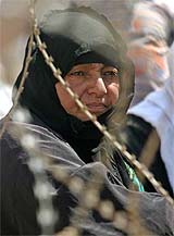 A woman waits outside Abu Ghraib prison as a security officer reads out a list of names of prisoners who will be allowed to visit their relatives