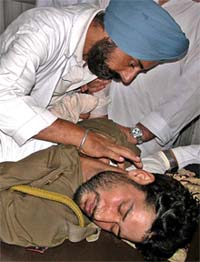 A doctor attends to a policeman wounded in a blast in Doda