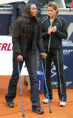 US tennis star Venus Williams leans on crutches as she walks past Amelie Mauresmo 