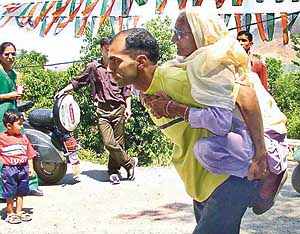 Devku Devi, a 95-year-old woman, is being carried piggyback by her son to the polling booth in Kandaghat in Solan district on Monday.