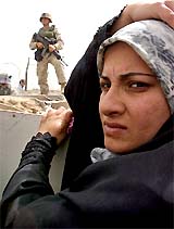 A woman stands outside the prison of Abu Ghraib while waiting to get information about a relative held inside