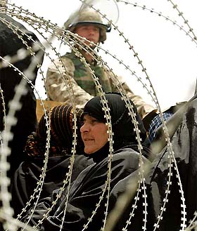 A US Marine stands guard as a crowd of Iraqi women wait outside Abu Ghraib prison 