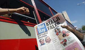 A bus commuter buys an evening tabloid