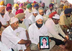 The father of Twinkle, who was killed in a mishap involving a train and a school van recently, holds her photo during a bhog