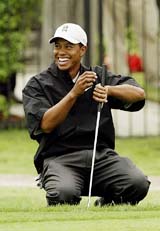 Tiger Woods laughs after playing partner John Cook sunk a long putt on the 18th hole 