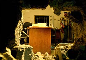 A man inspects a damaged office after it was hit by Israeli missiles in Gaza