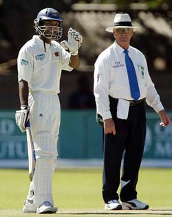 Sri Lankan batsman Kumara Sangakkara, watched by umpire Rudi Koertzen, waves to teammates after scoring 250 