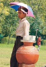 A child hawker waiting for thirsty customers near Rajghat, saving his head with a tiny umbrella in the Capital on Monday. 