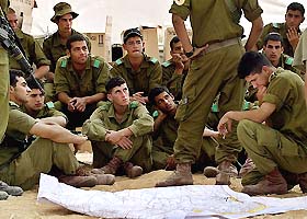 Israeli soldiers look at a map during a briefing at a camp near the entrance to Rafah