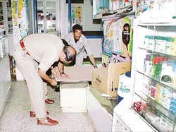 A policeman inspects the place where a bullet was fired at a chemist's shop in Sector 46