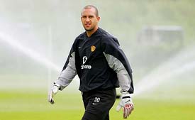 Manchester United goalkeeper Tim Howard of the USA walks past sprinklers during training at Carrington, near Manchester