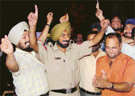 A policeman joins a bhangra crowd after hearing the news of Dr Manmohan Singh becoming the PM