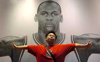 A student poses against a poster of NBA legend Michael Jordan at a stadium in Beijing 