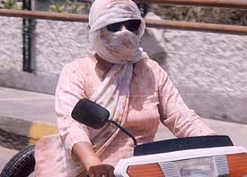 A woman scooterist covers face to beat the heat