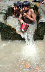 Young children cool off in a roadside water tank
