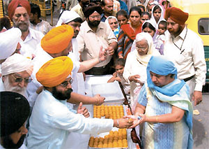 Congress activist Paramjeet Singh Pamma distributing sweets at Dr Manmohan Singh�s elevation as the first Sikh Prime Minister at Gurdwara Bangla Sahib in the Capital on Sunday. 