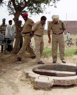 Policemen examine the well from where the body of a Dalit was found in Dhulkot village 