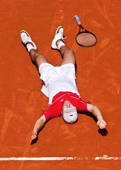 France's Fabrice Santoro lies on the clay after defeating compatriot Arnaud Clement
