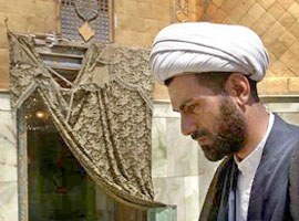 An Iraqi Shi'ite Muslim cleric walks past the damaged doorway of the shrine of Imam Ali in Najaf on Tuesday.