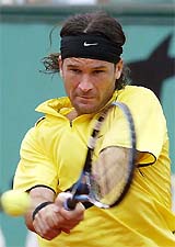 Carlos Moya of Spain hits a backhand return to to compatriot Fernando Vicente 