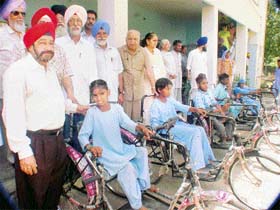 Dr Iqbal Singh Ahuja with recipients of tricycles which were given by Guru Nanak Charitable Trust, Mullanpur