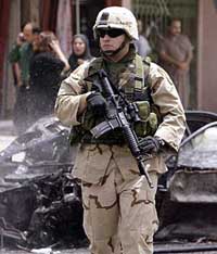 A US Army soldier attends the scene of a car bombing in the capital of Baghdad on Monday. A car exploded in a busy Baghdad street, killing at least two Iraqis.