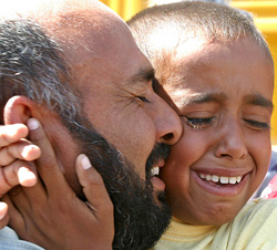 An Iraqi boy cries while hugging his father