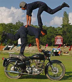 Jammu and Kashmir police personnel perform stunts on a motor cycle during the inaugural function of the 7th Mushtaq Memorial football tournament