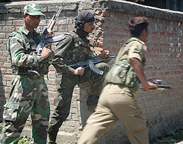 A jawan runs towards the site of an encounter as other soldiers take position behind the wall at Bogund village, some 75 km from Srinagar