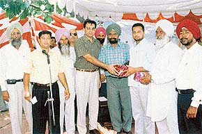 Mr Sandeep Hans, SDM, Amloh, honours two farmers who have topped in milk production in the subdivision at Ghatind village on Wednesday. 