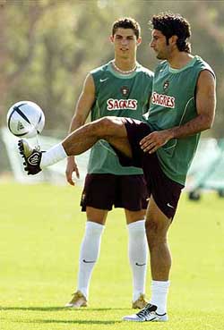 Portugal's Cristiano Ronaldo watches Luis Figo kicking a ball during a training session