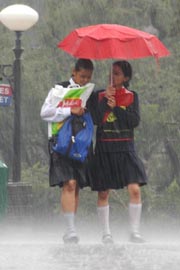 Two schoolgirls takes shelter under an umbrella as rain lashed Shimla on Tuesday