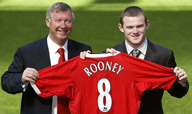 Wayne Rooney holds up his club shirt with manager Sir Alex Ferguson on the pitch at Old Trafford in Manchester 