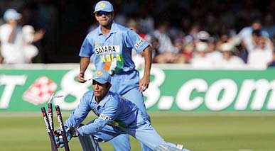 Debutant wicketkeeper Dinesh Karthick takes the bails off England's Paul Collingwood's wicket as Rahul Dravid looks on