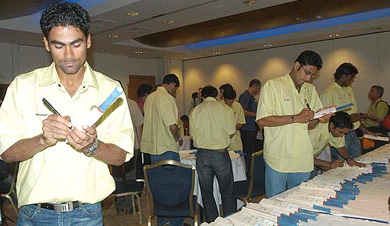 Indian cricketers Mohammed Kaif and Anil Kumble sign miniature cricket bats for sponsors during a media briefing in London
