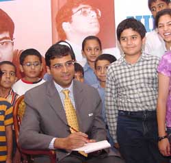 World chess champion Viswanathan Anand (C) signs autographs for children during a homecoming celebration organised by NIIT. The event was organised to felicitate Anand for his accomplishments in 2004 in chess in New Delhi on Friday. 