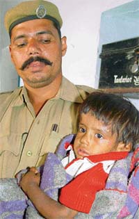 A policeman holds the baby girl who was abandoned in fields of Devi Nagar village near Dera Bassi