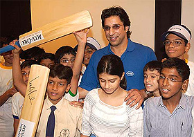Former Pakistani cricket captain Wasim Akram poses with children after inaugurating a diabetic awareness roadshow