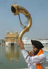A Sikh devotee blows a traditional horn, during nagar kirtan on the eve of the birth anniversary of Guru Ram Das, in Amritsar on Friday. 