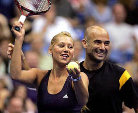 Anna Kournikova of Russia gets a little lighthearted help on her serve from Andre Agassi during their doubles match at the World TeamTennis Smash Hits event 