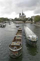 River barges drive at a snail�s pace on the Seine river near Notre Dame Cathedral, seen in background, in Paris, on Sunday. Unhappy river barges� operators slowed the Seine river traffic to protest the high price of oil. 