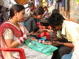 Women get Mehndi applied on their palms ahead of the Karva Chauth festival