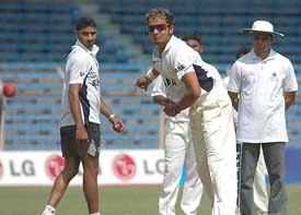 Left-arm spinner Murali Kartik bowls as Harbhajan Singh and Pakistan umpire Alam Daar look on during practice session at Wankhede Stadium