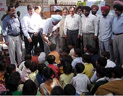 The Deputy Commissioner, Mr Mandeep Singh, distributes food items among schoolchildren in a school at Moga