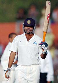 Dinesh Mongia of Board President's XI raises his bat after completing his century on the second day of a three-day match against South Africa in Jaipur