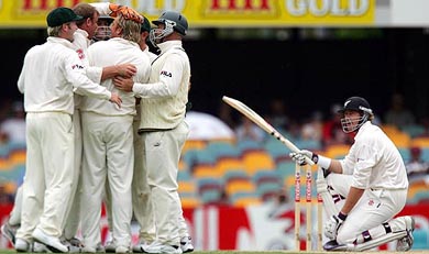 New Zealand�s Jacob Oram kneels beside the stumps as Australian team members celebrate his dismissal on day four of the first Test in Brisbane